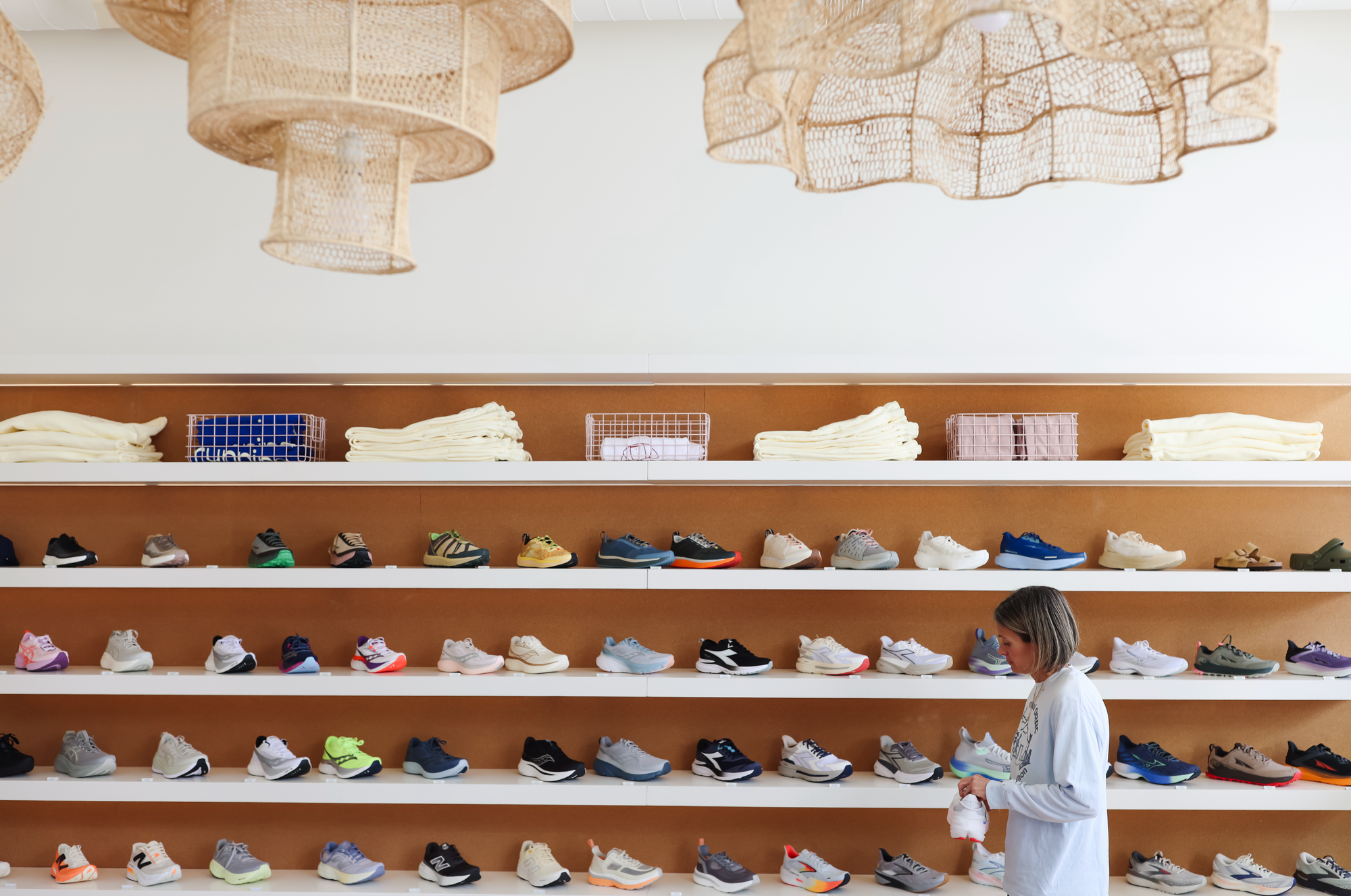Shelf displaying various shoes with a person browsing in a store setting.